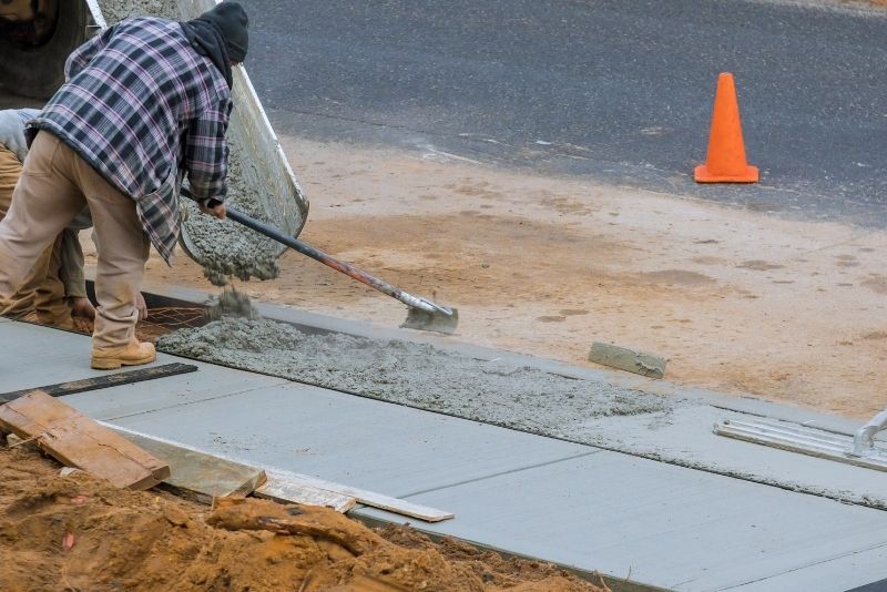 local concrete specialist using concrete rake while pouring concrete