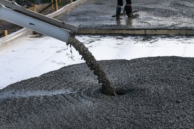Pouring wet concrete into the forms until they are full to the top edge